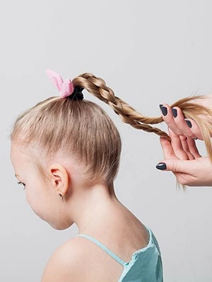 Egy kislány zsinórra fonja a frizurákat